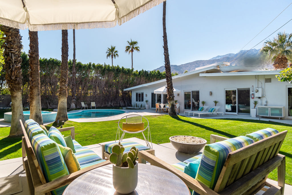 Original Curated Hill House backyard of palm springs house with hot tub, pool, grass area and outdoor seating with mountains in the background